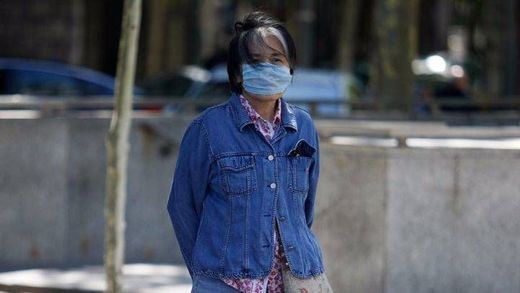 Una turista japonesa con mascarilla para evitar la contaminación atmosférica en el paseo de la Castellana de Madrid