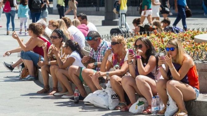 Turistas descansando en la fuente de la Puerta del Sol 