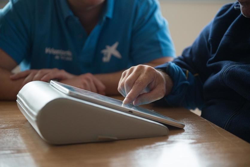 Voluntaria “la Caixa” forma a una persona en el uso de tablets para comunicarse con sus familiares
