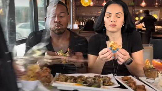 Pareja de youtubers comiendo mientras un coche atraviesa el cristal del restaurante