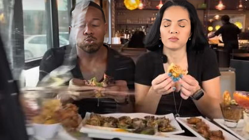 Pareja de youtubers comiendo mientras un coche atraviesa el cristal del restaurante